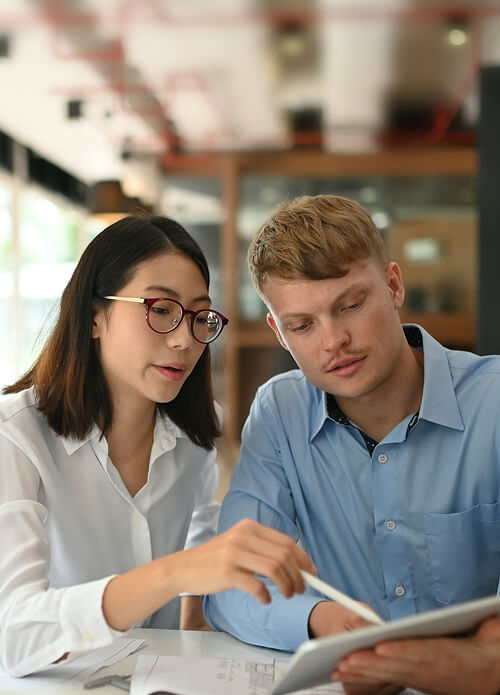 Two people reviewing a document together at a table in an office setting.