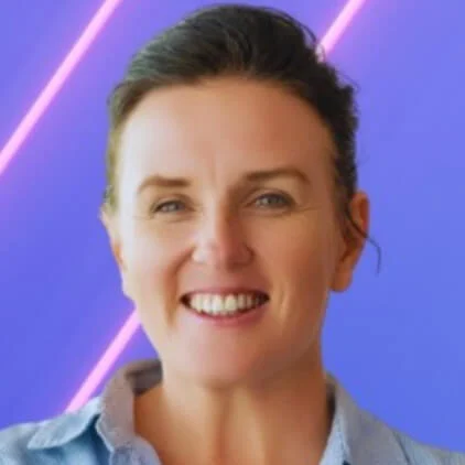 Leena Beker with brown hair in a casual updo smiles in front of a purple background with diagonal pink neon lines.